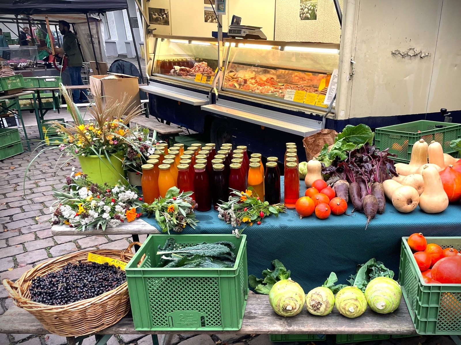 Marktstand von Lamm & Apfel mit Säften, Gemüse, Blumen und Fleischwaren